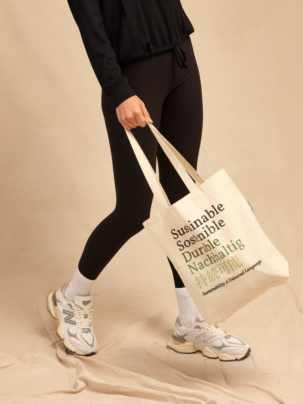Minimalist off-white organic cotton tote bag with dark green multilingual sustainability text