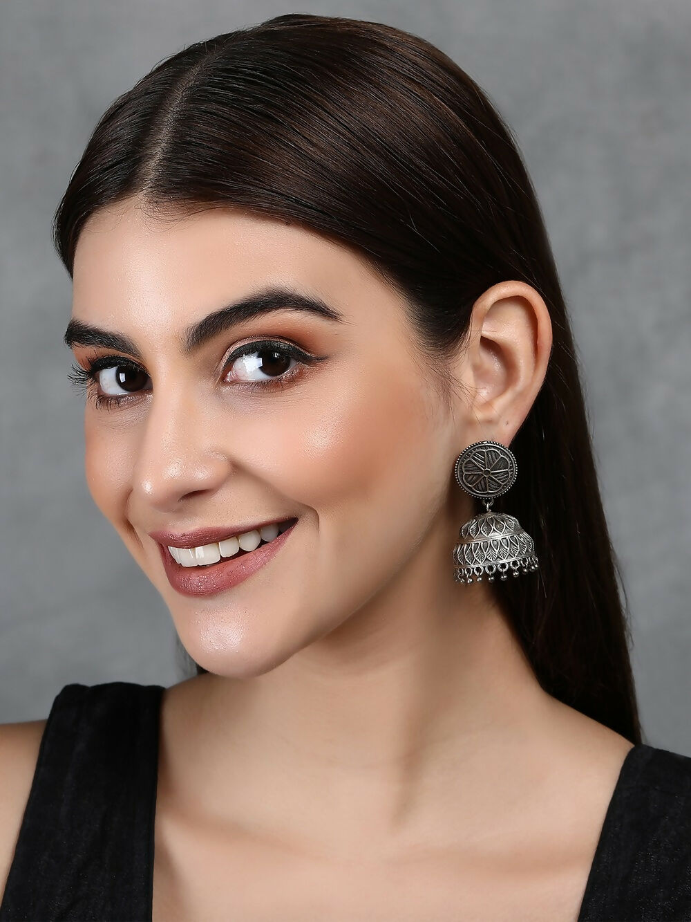 Silver tone brass jhumka earrings with intricate geometric patterns and stone details