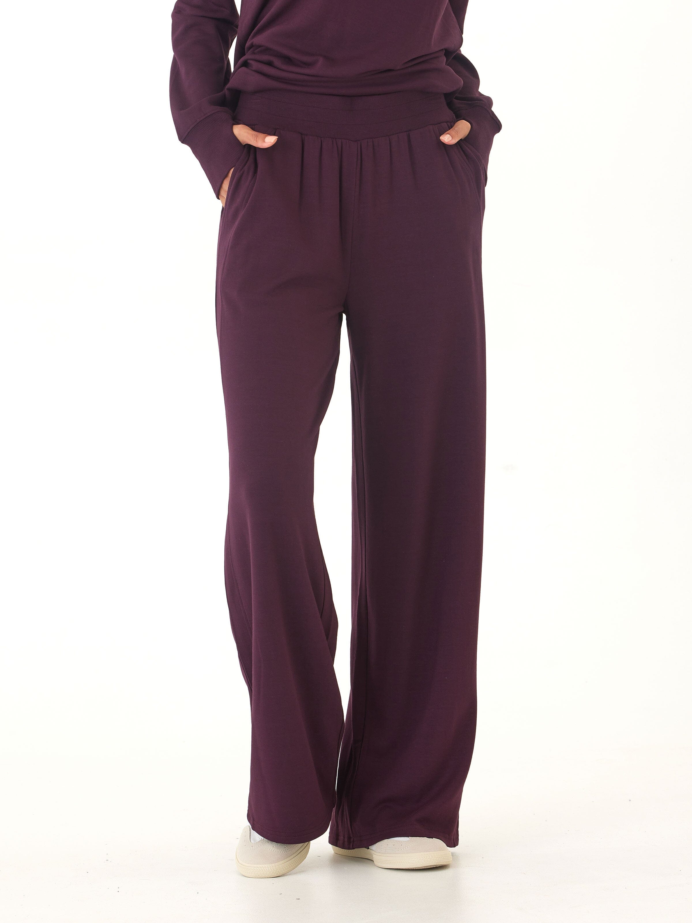 Close up of dark purple Core Feather Fleece sweatpants showing the soft knit texture and fluid drape.