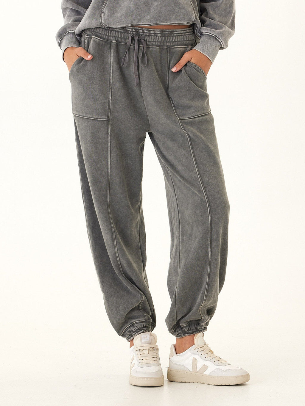 Woman wearing charcoal and grey mineral wash cotton fleece joggers with a relaxed, tapered fit.