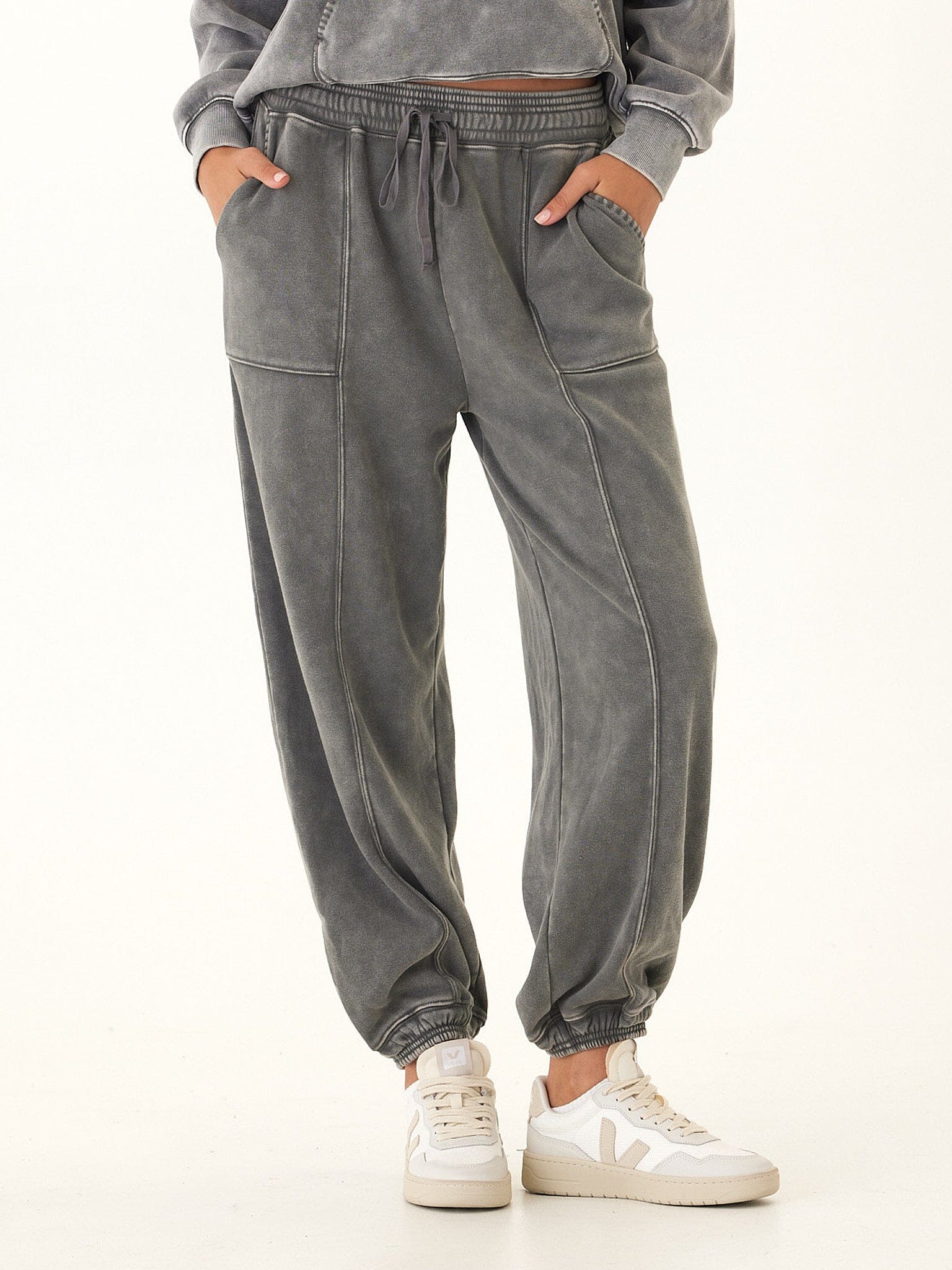 Woman wearing charcoal and grey mineral wash cotton fleece joggers with a relaxed, tapered fit.