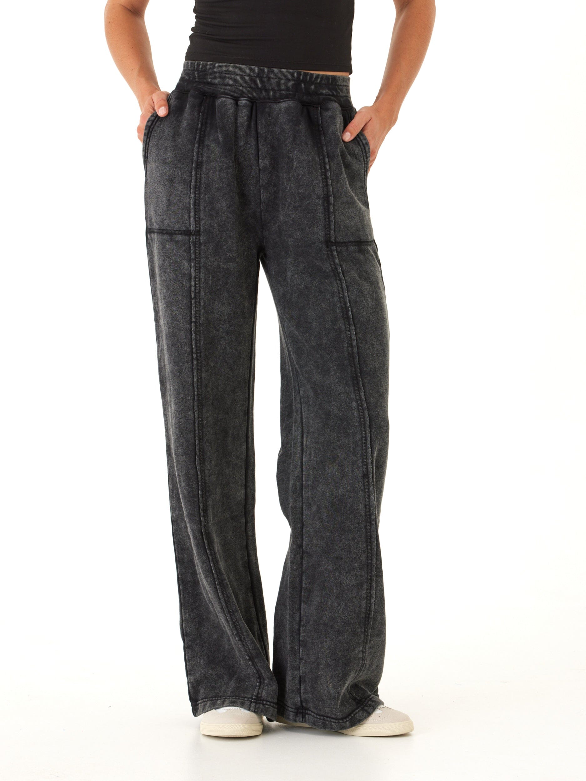 Woman wearing charcoal mineral wash wide leg knit pants with elastic waistband and exposed seams.