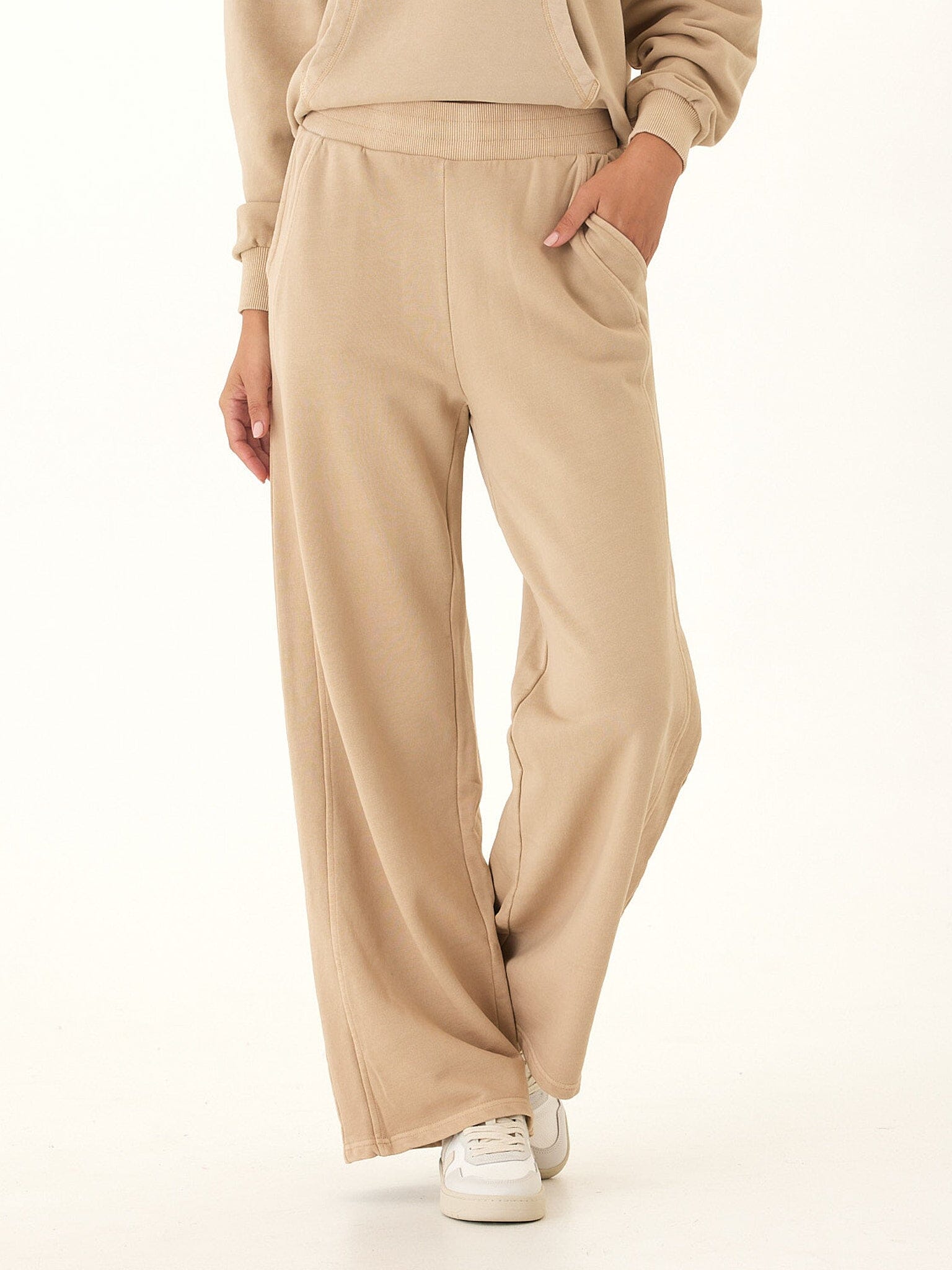High-rise wide-leg Core Feather Fleece sweatpants in warm beige, shown in a relaxed lounge fit.
