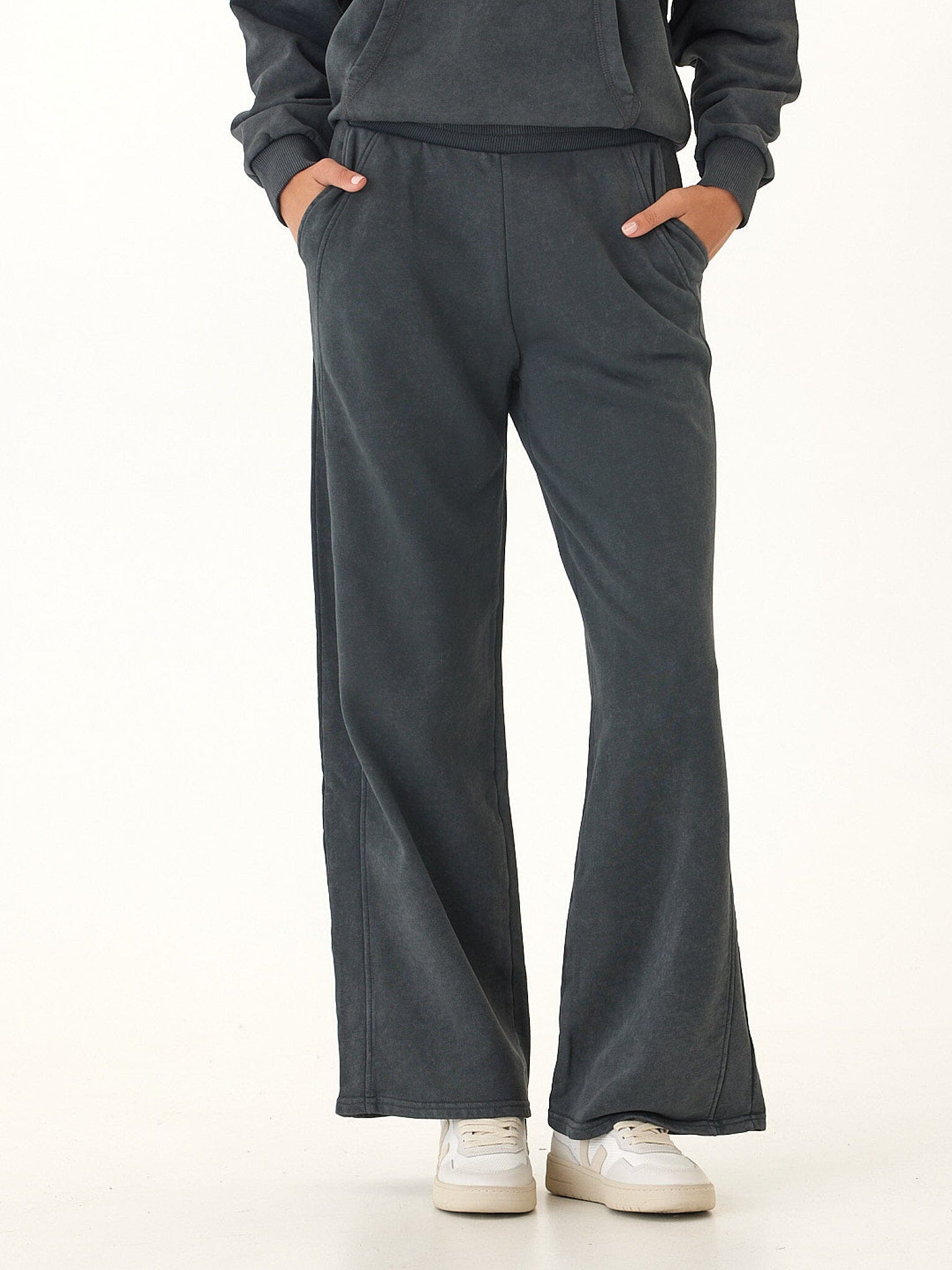 Women wearing relaxed wide-leg Core Feather Fleece sweatpants in charcoal grey with an elastic waistband.