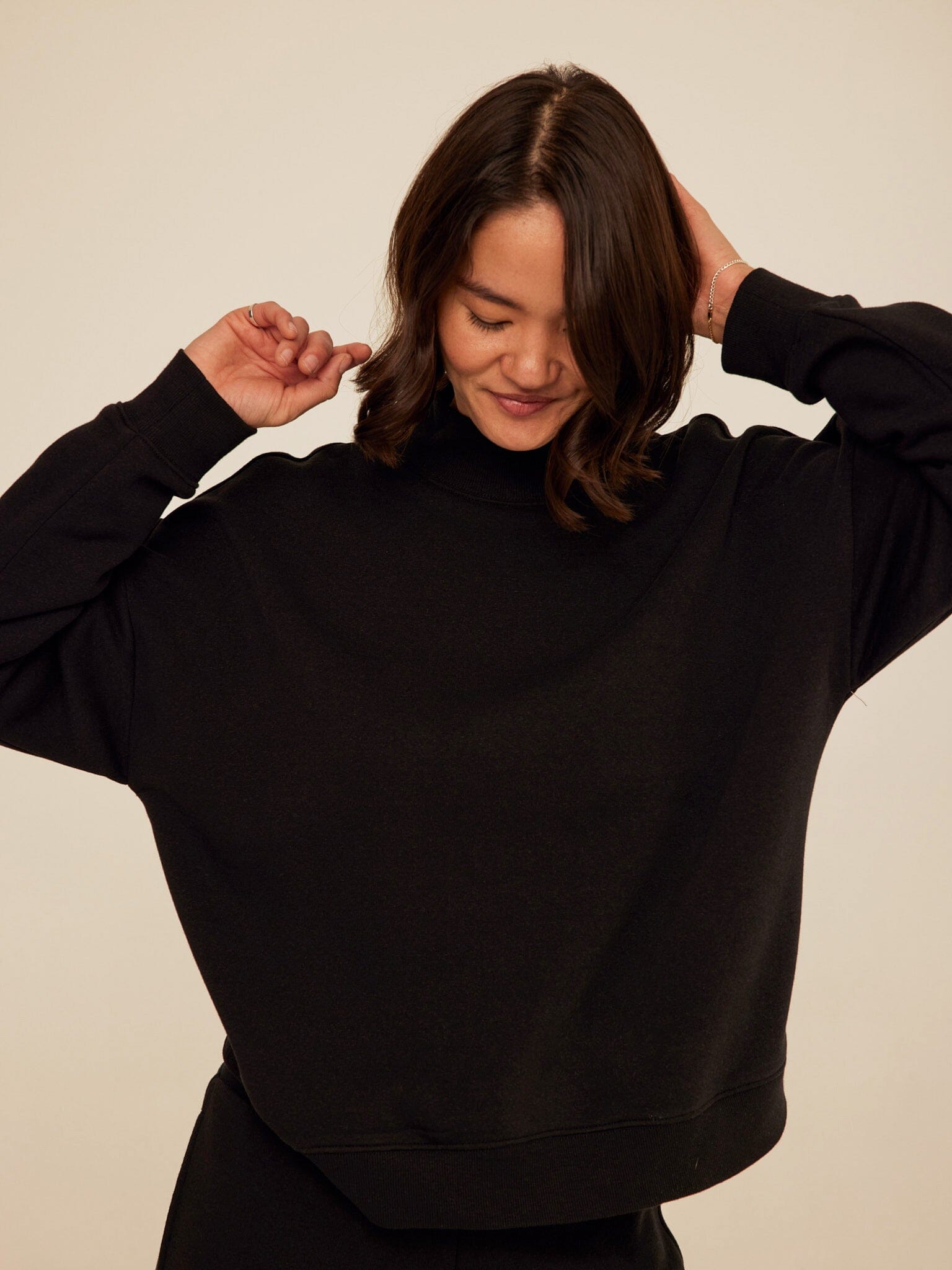 Model wearing a soft, relaxed fit triblend fleece mock neck pullover in a neutral tone