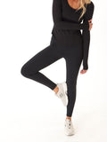 Woman wearing Monica Mid Rise Full Length Leggings in solid black, featuring a tapered fit and pull-on waistband.