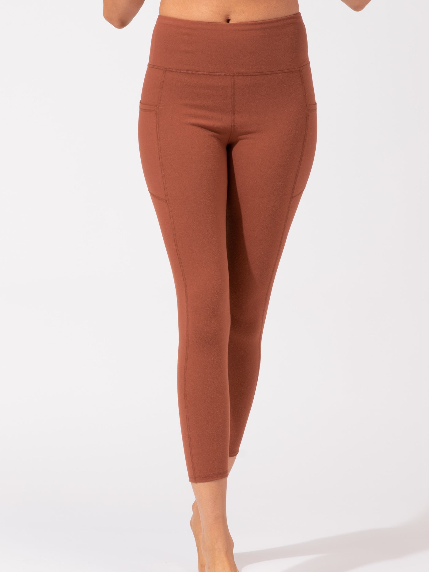 Rust colored high-rise ankle length leggings with side pockets.