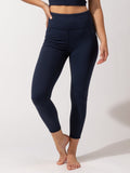 A pair of solid navy blue high-rise ankle-length leggings with side pockets, shown in a sporty, minimalist style.
