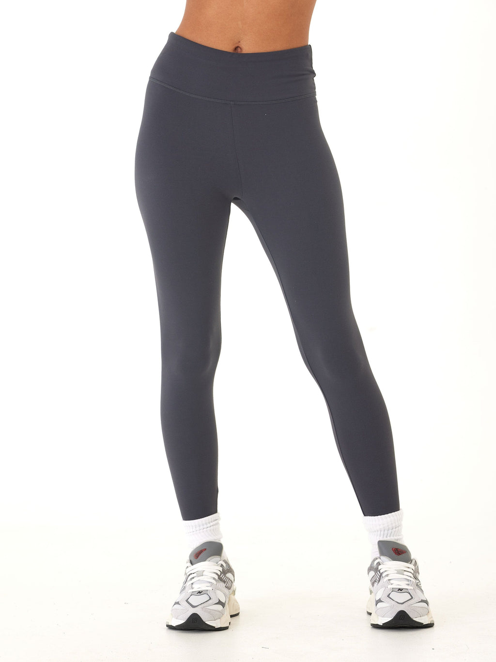 Model wearing solid charcoal grey high-rise ankle-length leggings with a sporty, fitted silhouette.