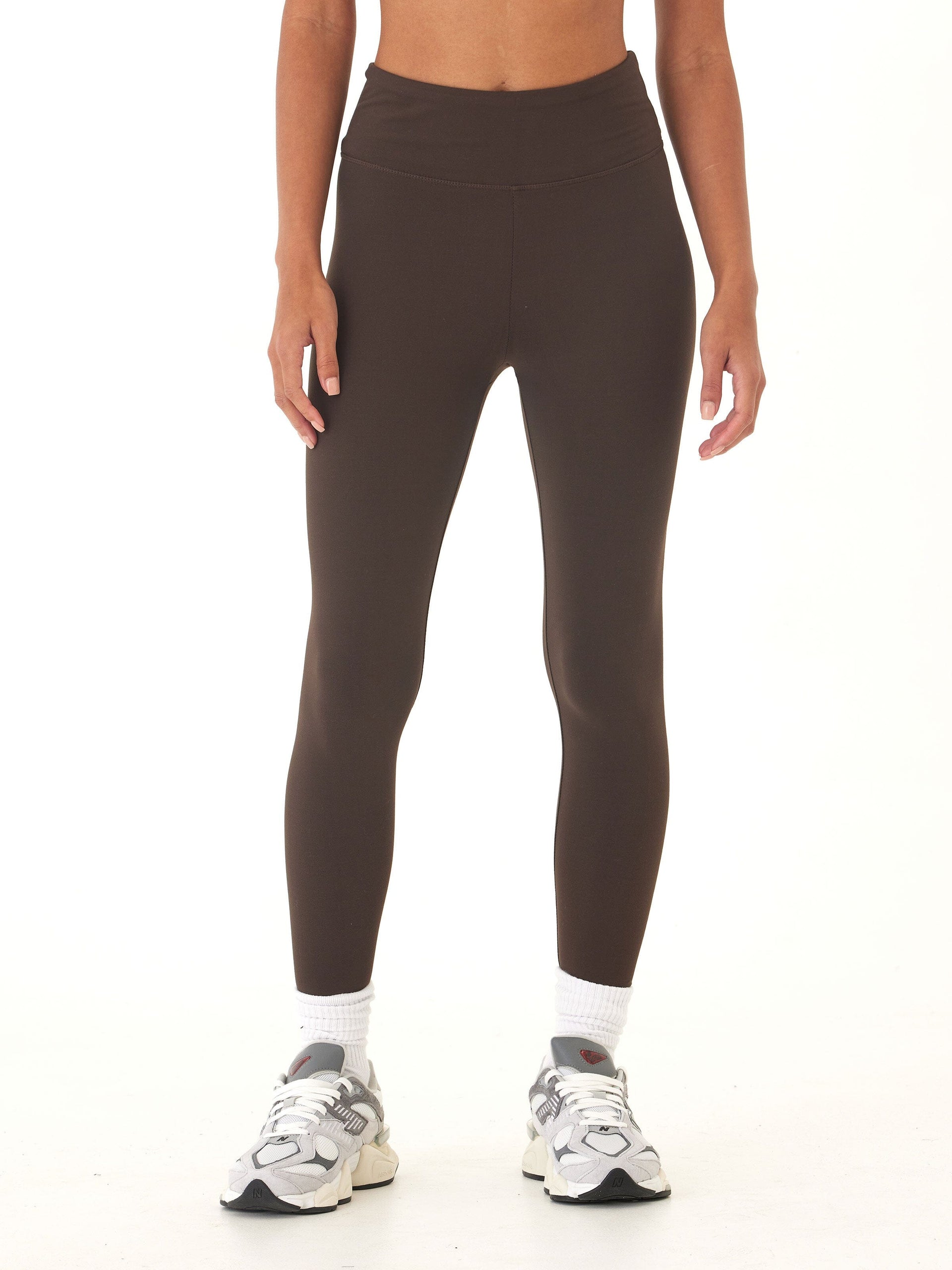 A pair of solid brown high-rise ankle length leggings in a fitted, sporty style.
