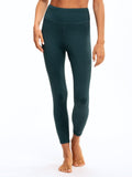 Woman wearing dark green Comfort Fit high-rise ankle length leggings in a sporty, minimalist setting.