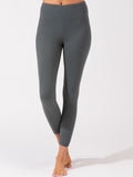 Woman wearing charcoal gray high-rise ankle-length leggings in a sporty, minimalist athletic style.