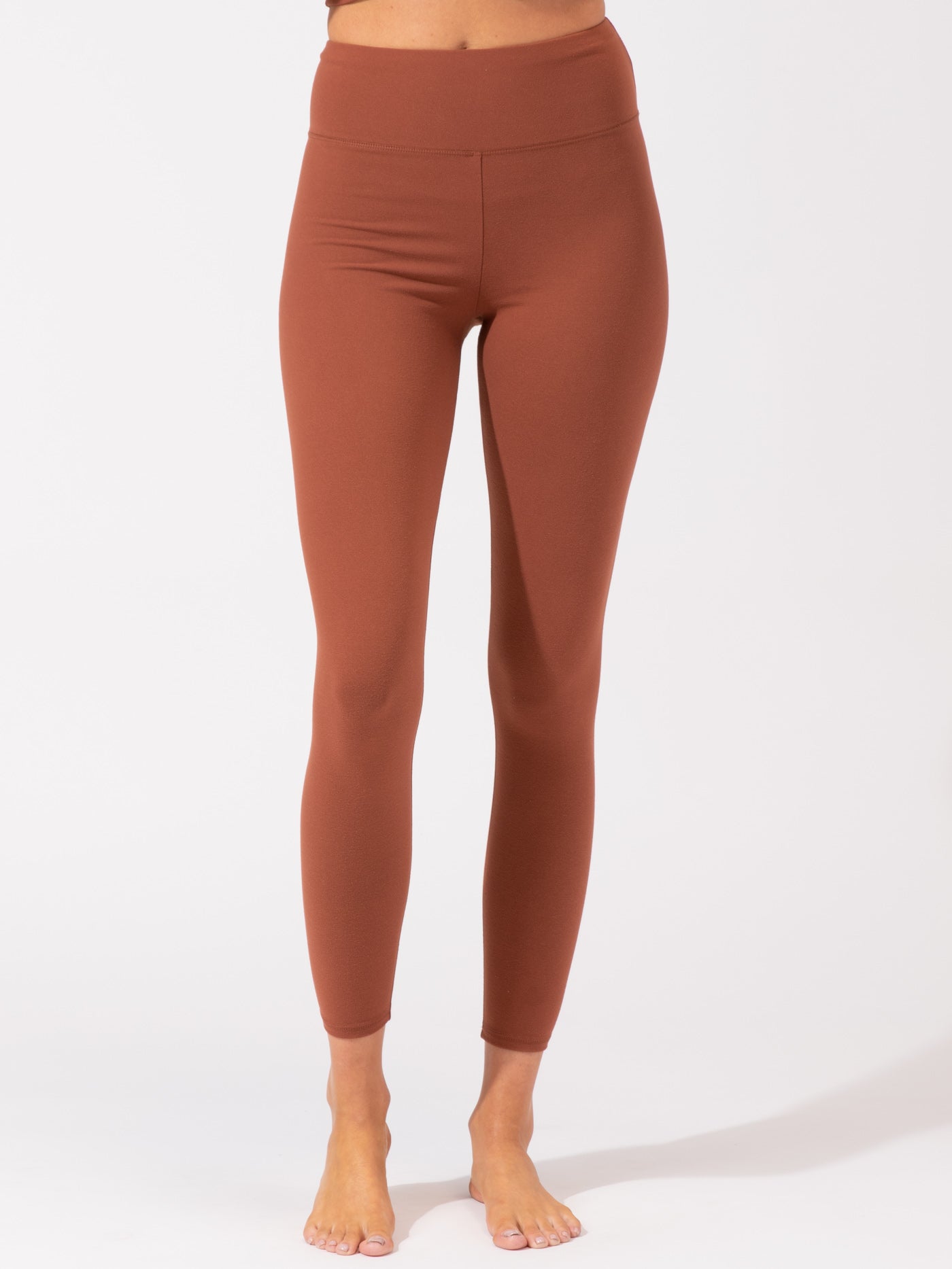 Women wearing high-rise full length athletic leggings in a warm terracotta tone