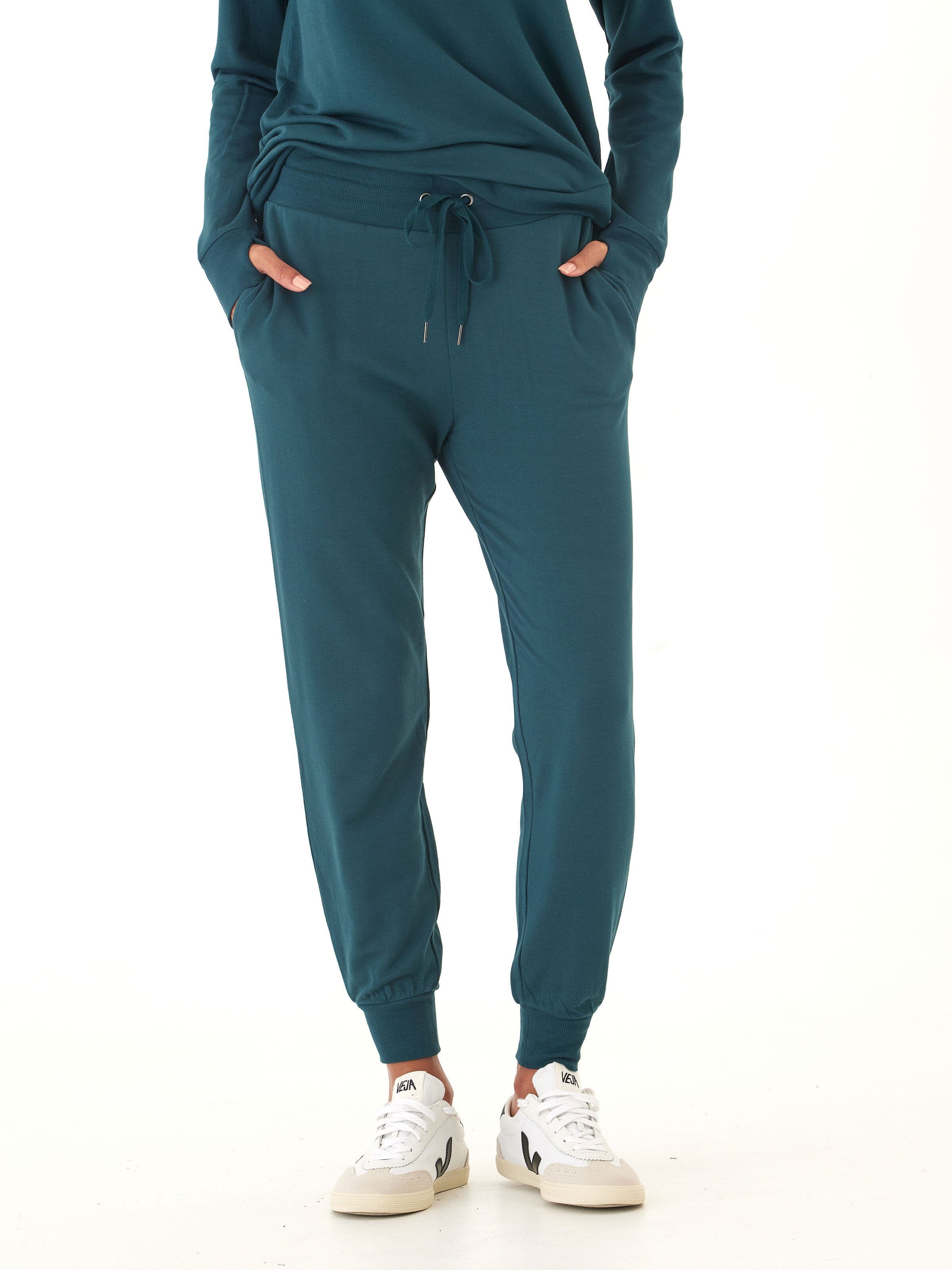 Women wearing deep teal Core Feather Fleece joggers with a tapered, relaxed fit and ribbed cuffs.