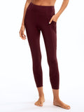 A pair of high-rise 7/8 length burgundy sport leggings with side pockets and a fitted silhouette.