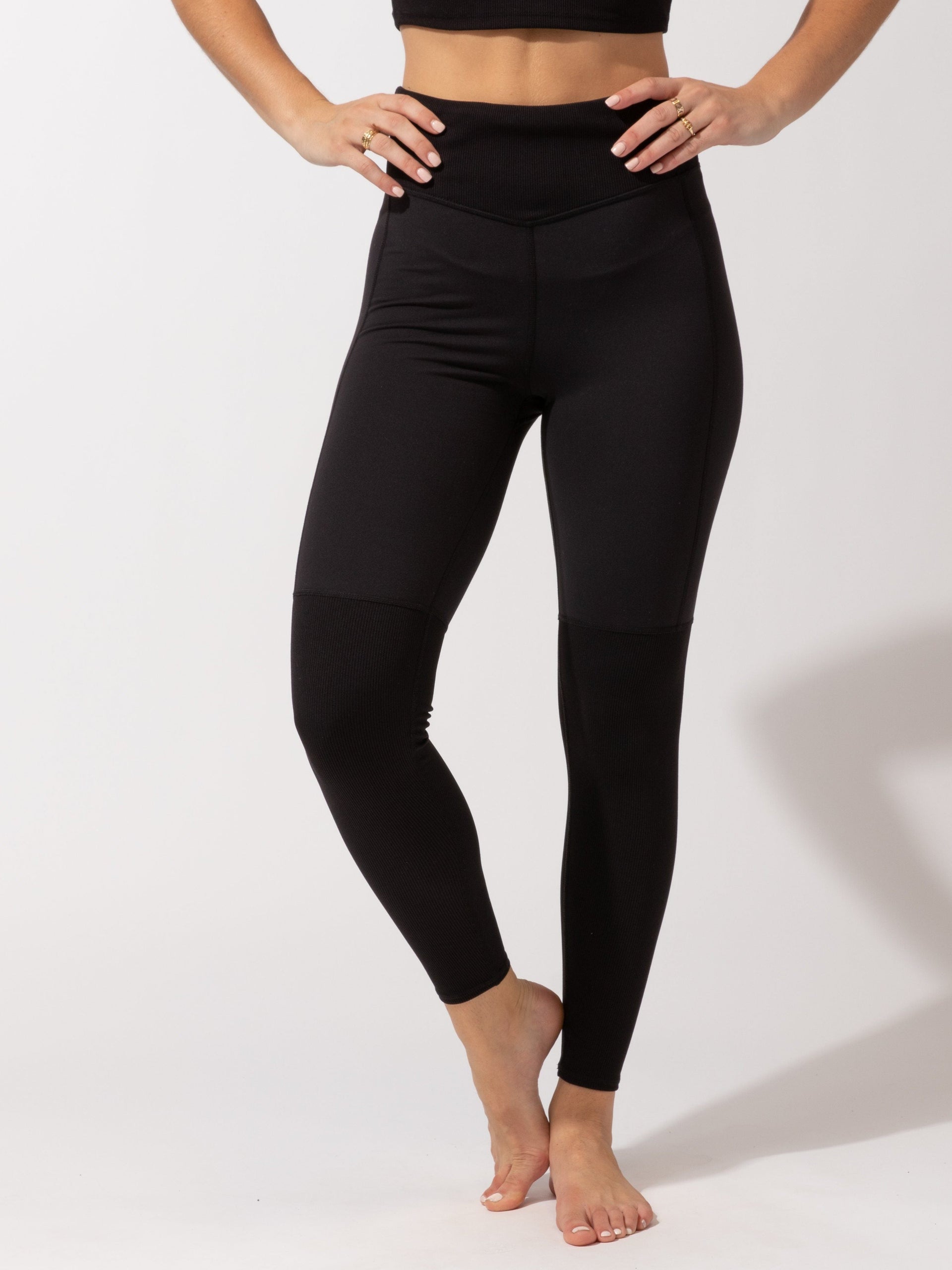 Woman wearing black Mikayla full-length leggings featuring a subtle silver waistband logo