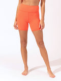 Woman wearing orange high-rise Sylvana active shorts in a sporty, minimalist style.