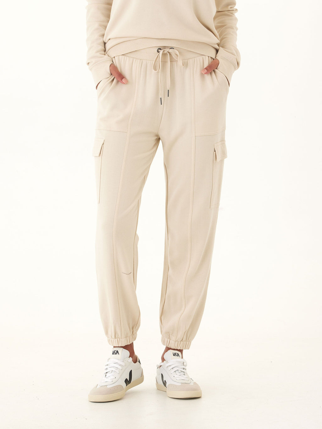 Woman wearing Margot Feather Fleece Cargo Joggers in beige with utility pockets.