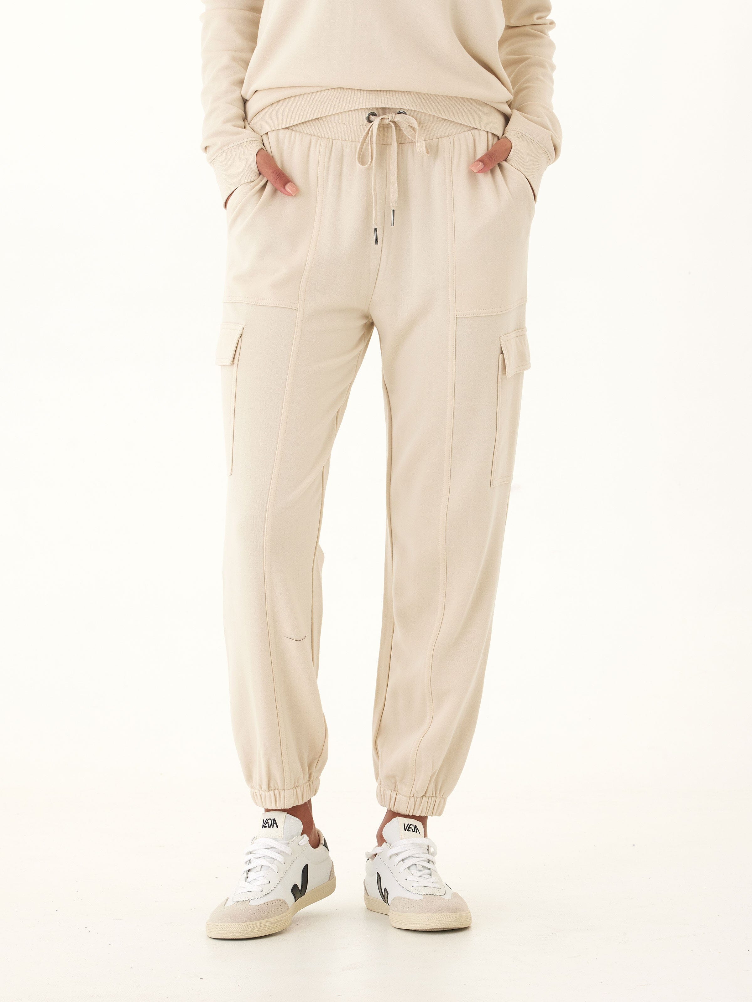 Woman wearing Margot Feather Fleece Cargo Joggers in beige with utility pockets.