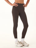 Woman wearing Elena high rise 7/8 leggings in espresso with a reflective circle logo on the back