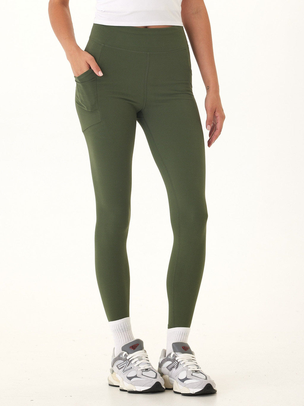Woman wearing Elena High Rise 7/8 leggings in olive green with functional side pockets