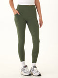 Woman wearing Elena High Rise 7/8 leggings in olive green with functional side pockets