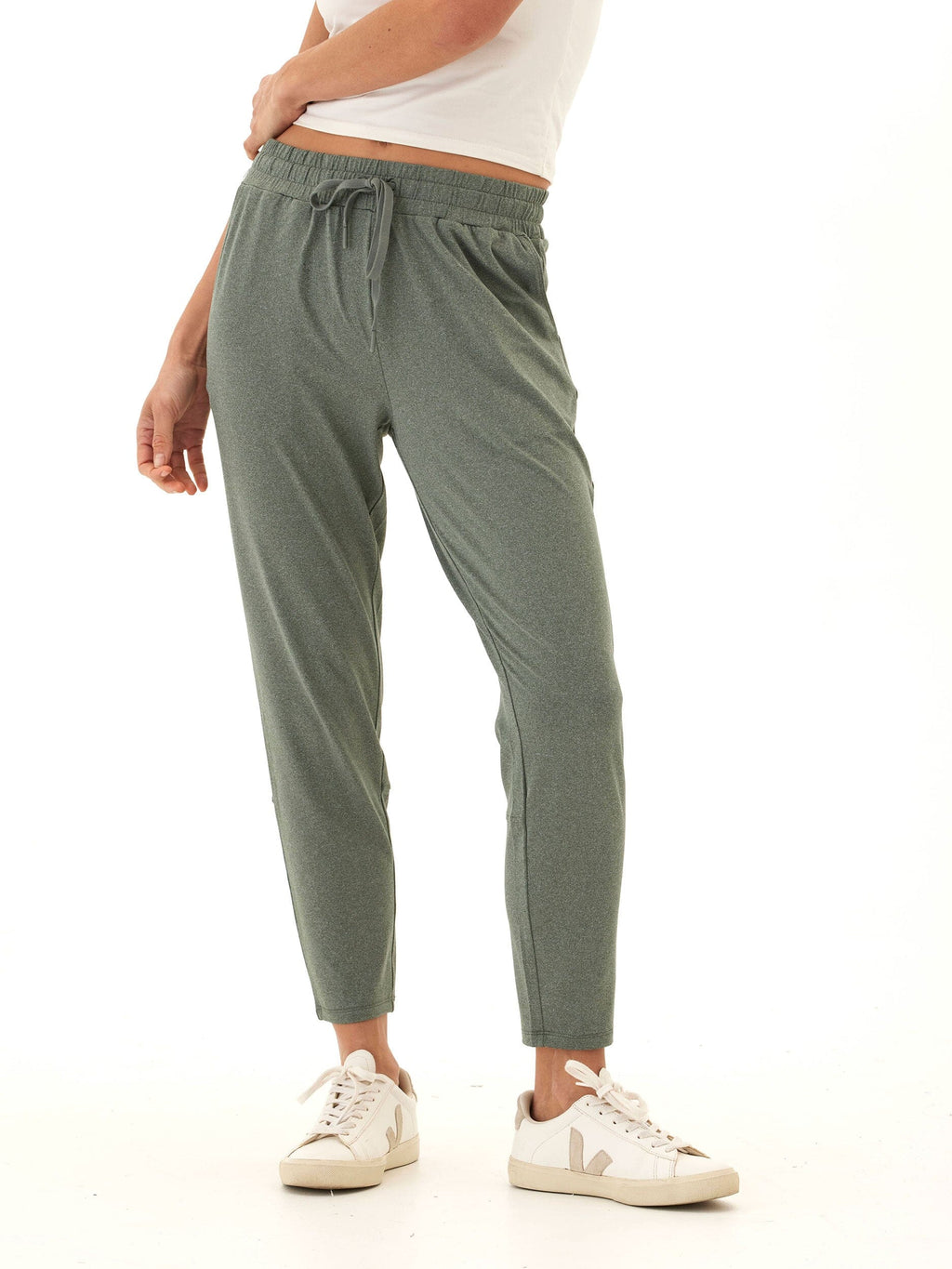 Woman wearing Lacey Luxe Jersey Pants in sage green for a minimalist athleisure look.
