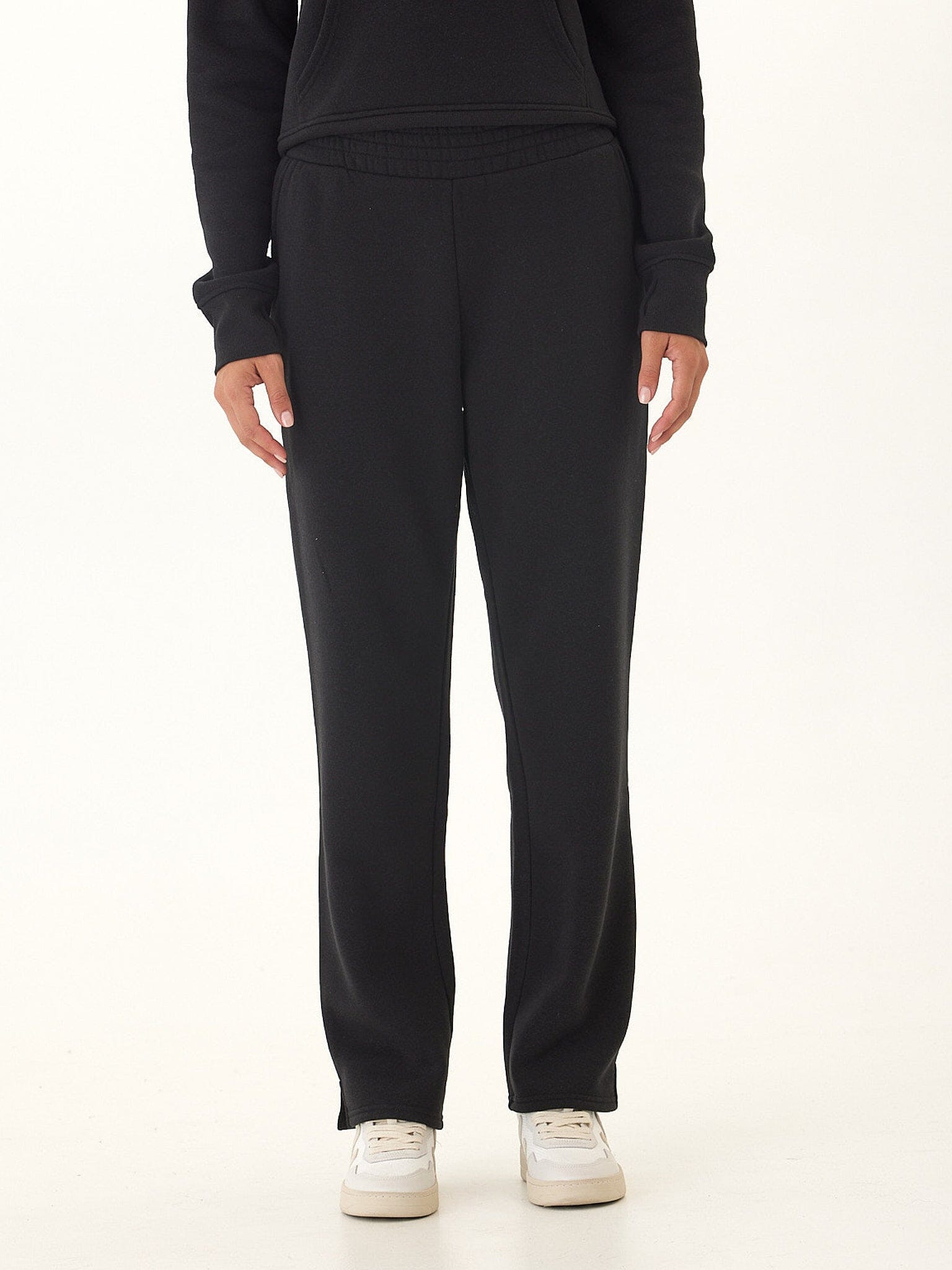 Woman wearing black minimalist athleisure triblend fleece pants in a studio setting.