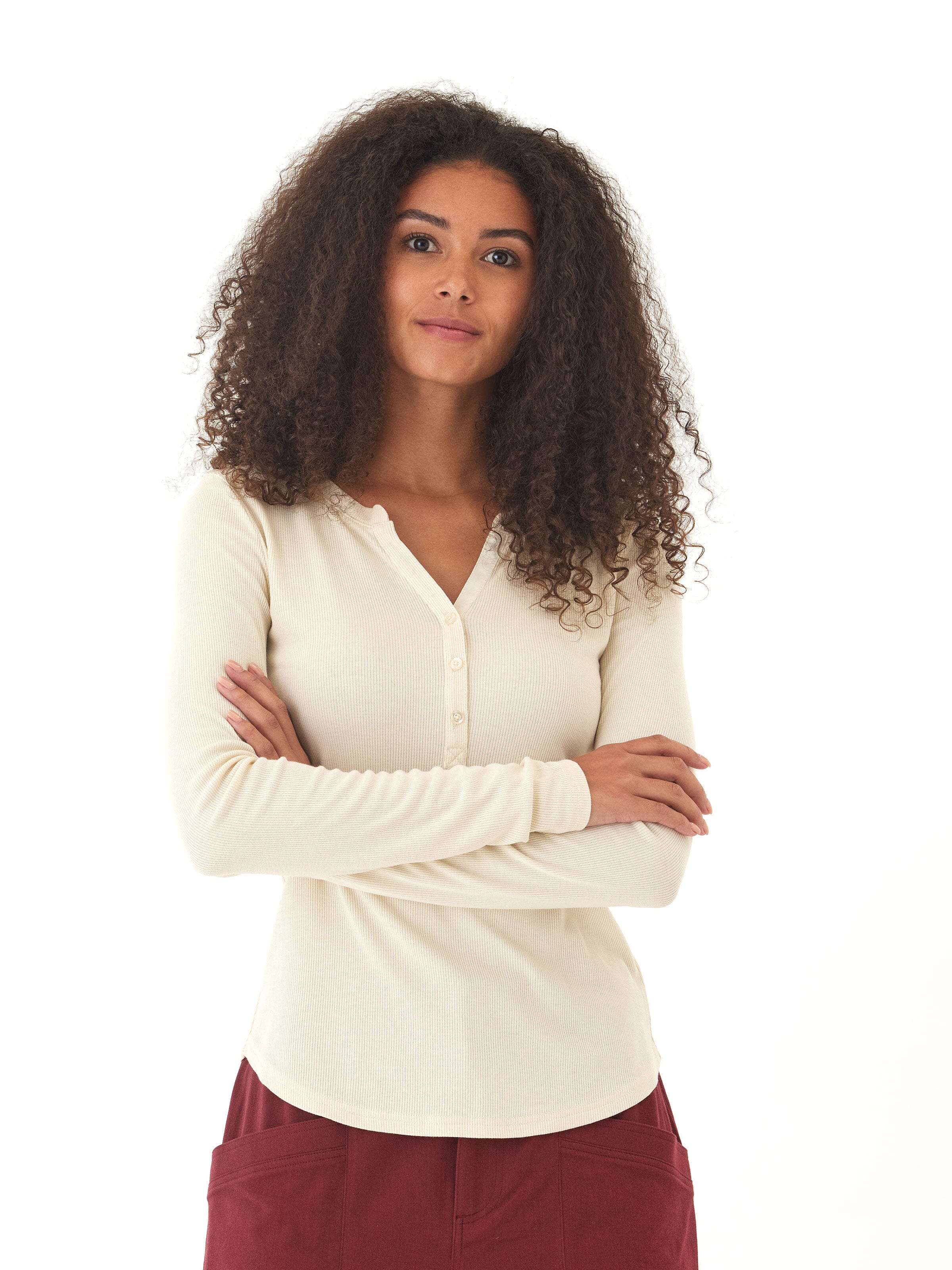 Woman wearing an off-white long sleeve rib-knit henley with functional buttons.
