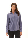 A woman wearing a soft periwinkle blue relaxed fit knit fleece button-up shirt with a collared neckline.