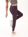 Dark purple high-rise 7/8 leggings with circular branding logo on the waistband.