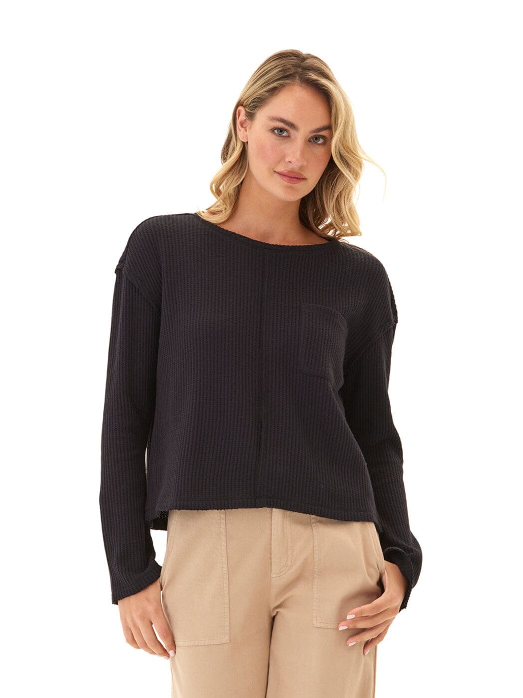 A minimalist black long sleeve top in a soft knit texture worn by a woman.