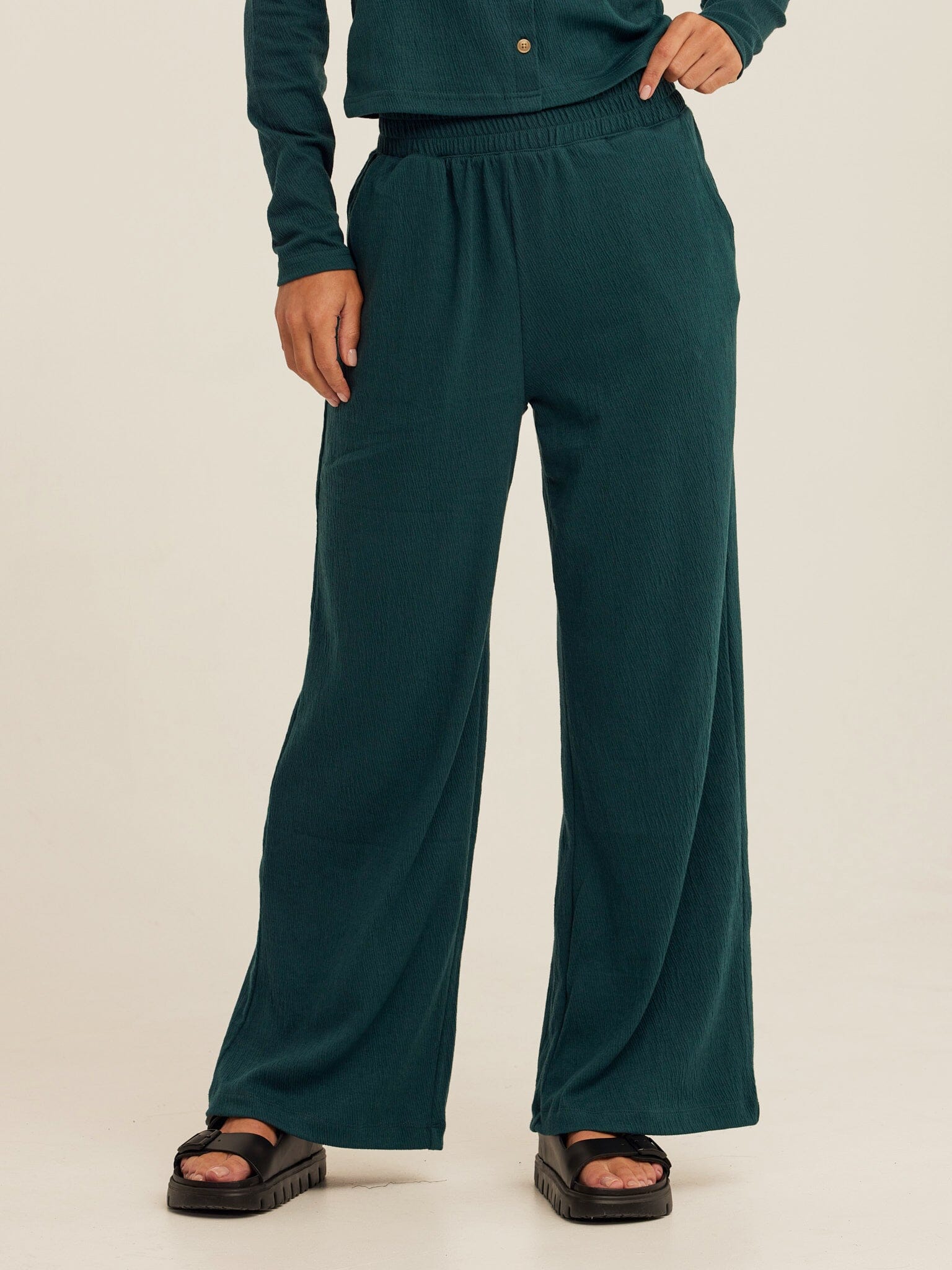 Dark green smocked jersey wide leg pants with an elastic waist in a soft knit fabric.