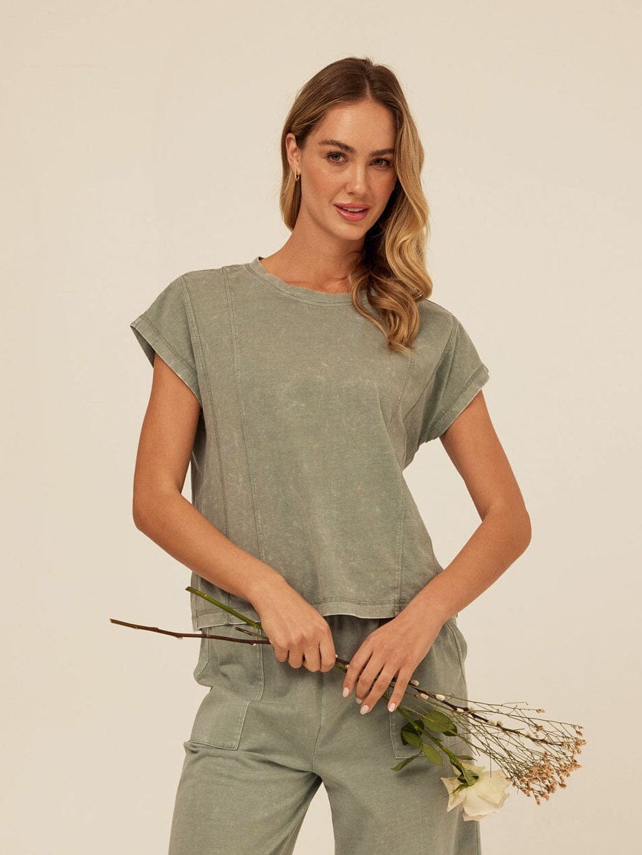 Close up of a woman wearing a muted sage green mineral wash crew neck knit tee with a relaxed fit.