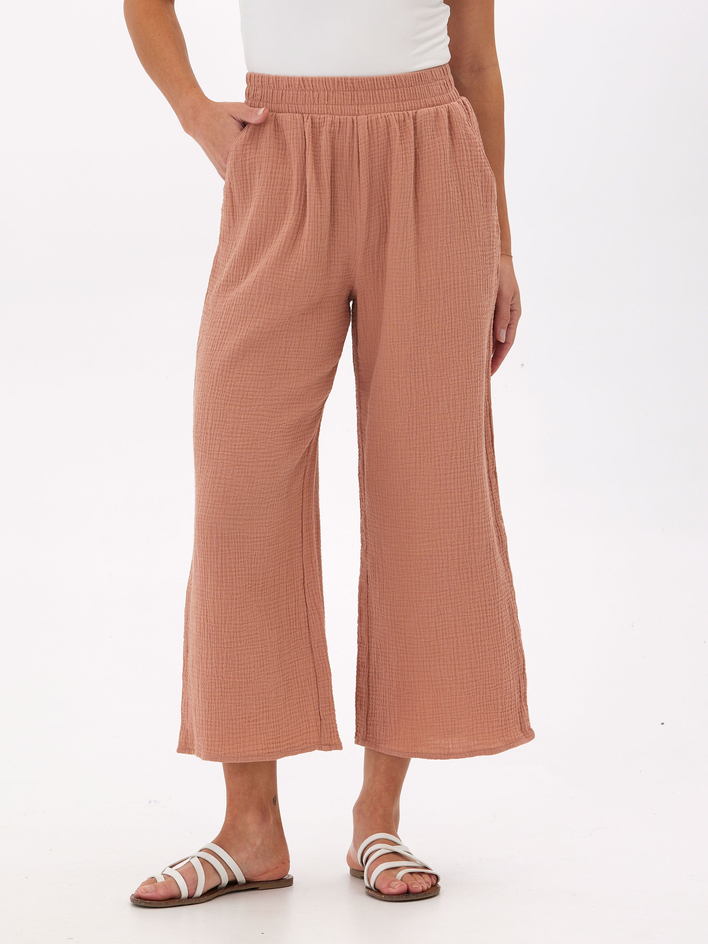 Woman wearing dusty rose organic cotton wide leg gauze pants with a relaxed, cropped fit.