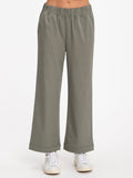 Model wearing a pair of muted olive green, wide-leg, mid-rise Georgie stretch twill pants in a casual setting.