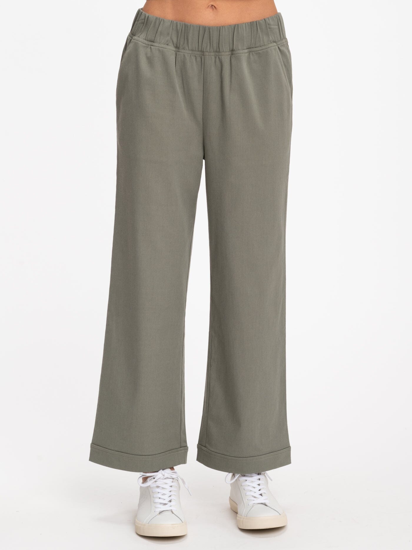 Model wearing a pair of muted olive green, wide-leg, mid-rise Georgie stretch twill pants in a casual setting.