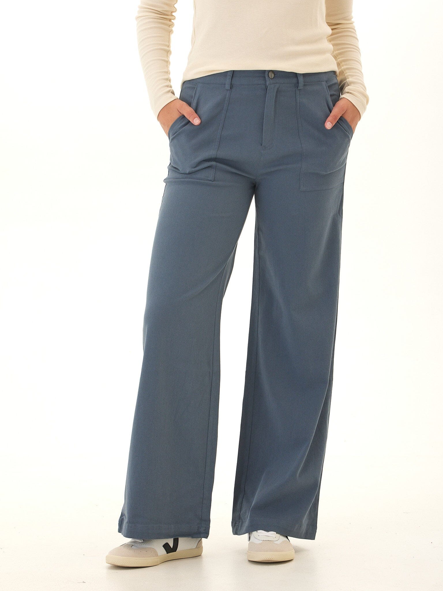 Model wearing Pamela high-rise wide leg pants in dusty slate blue stretch twill fabric.