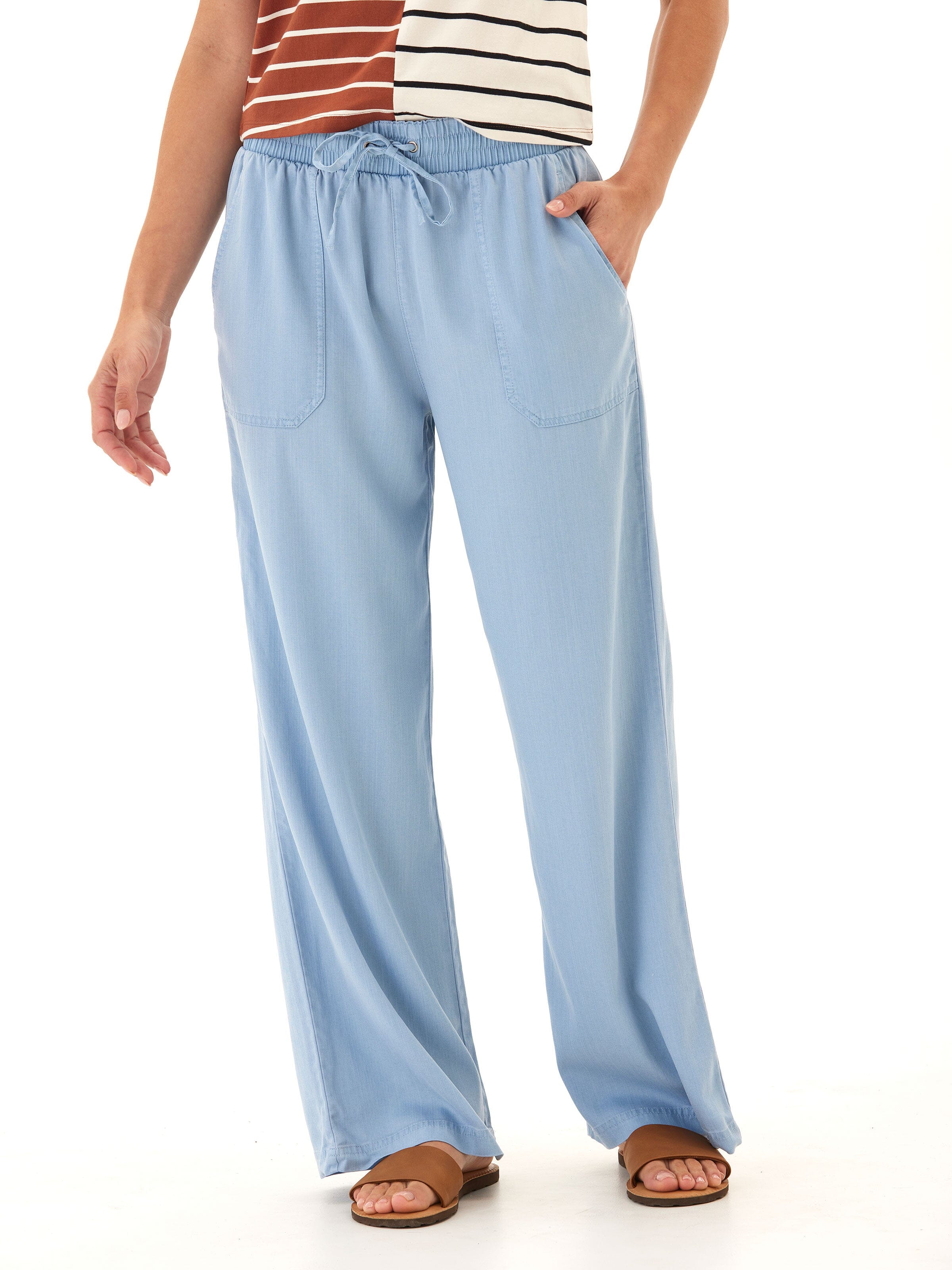 Woman wearing wide-leg light blue stretch chambray pants with drawstring waist and patch pockets
