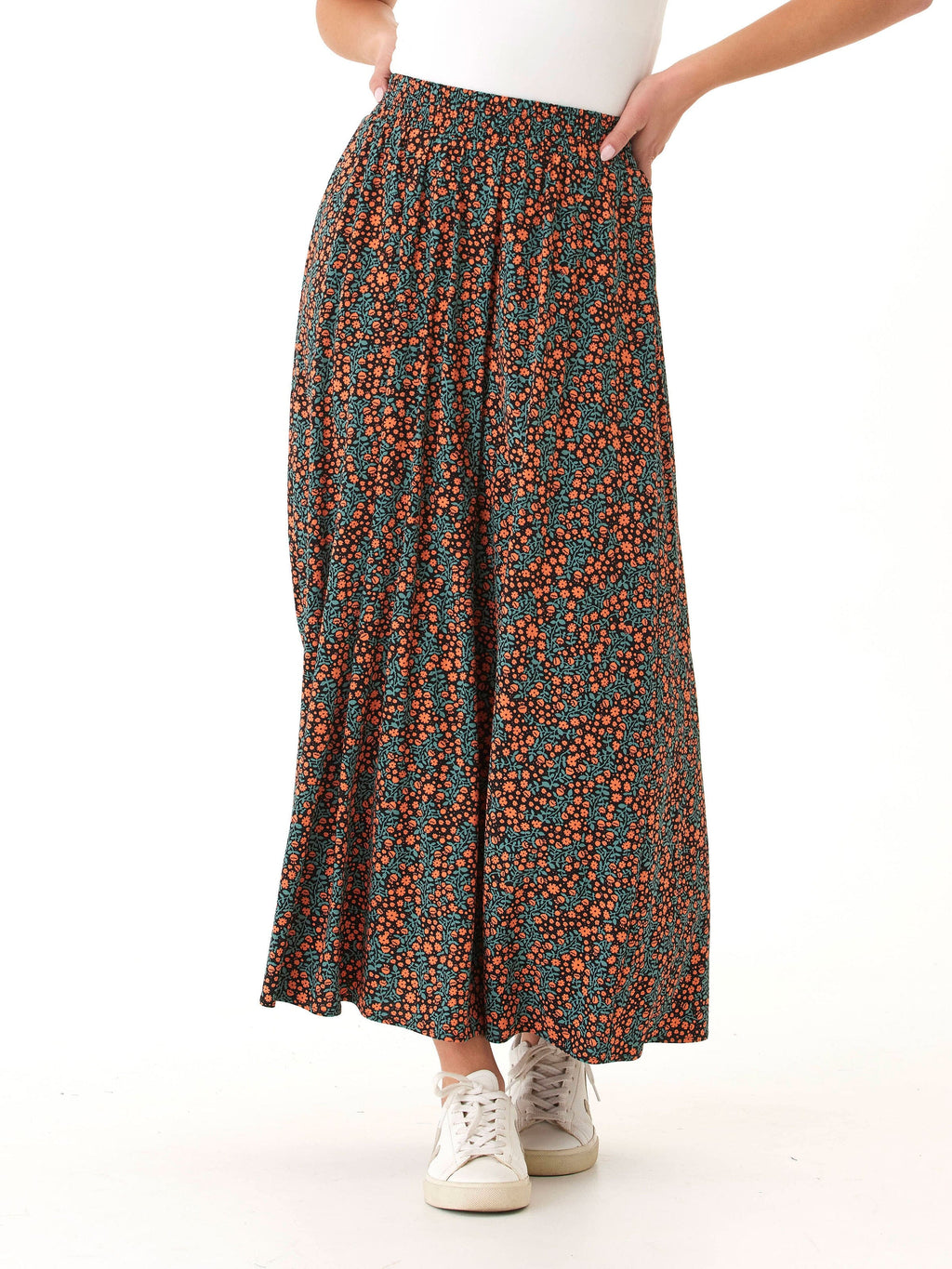 Woman wearing an Anastacia floor-length maxi skirt with a black, orange, and teal floral print in a relaxed A-line silhouette.