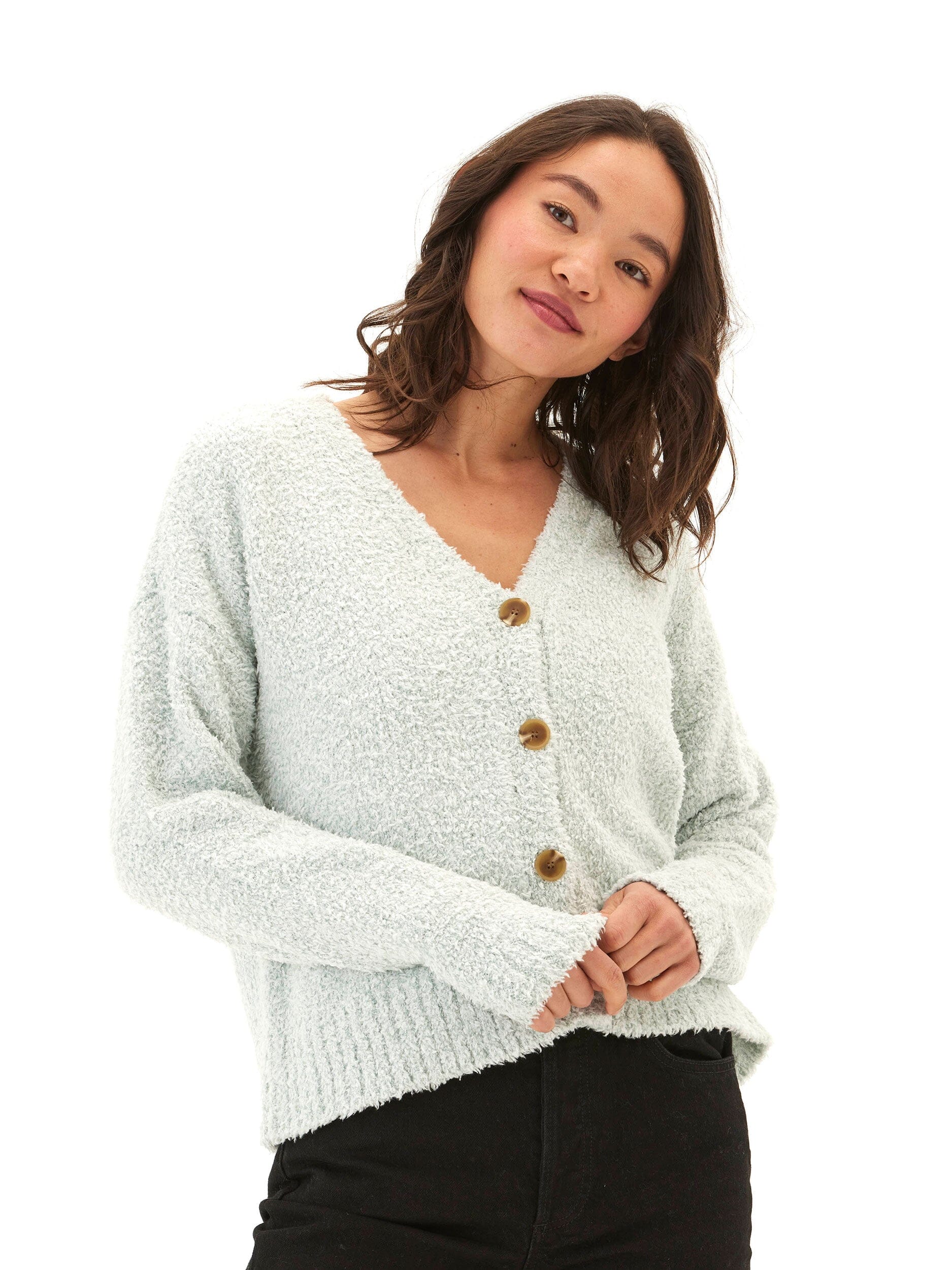 A woman wearing a soft mint-green boucle knit cardigan with a V-neckline and button-front closure in a cozy, minimalist setting.