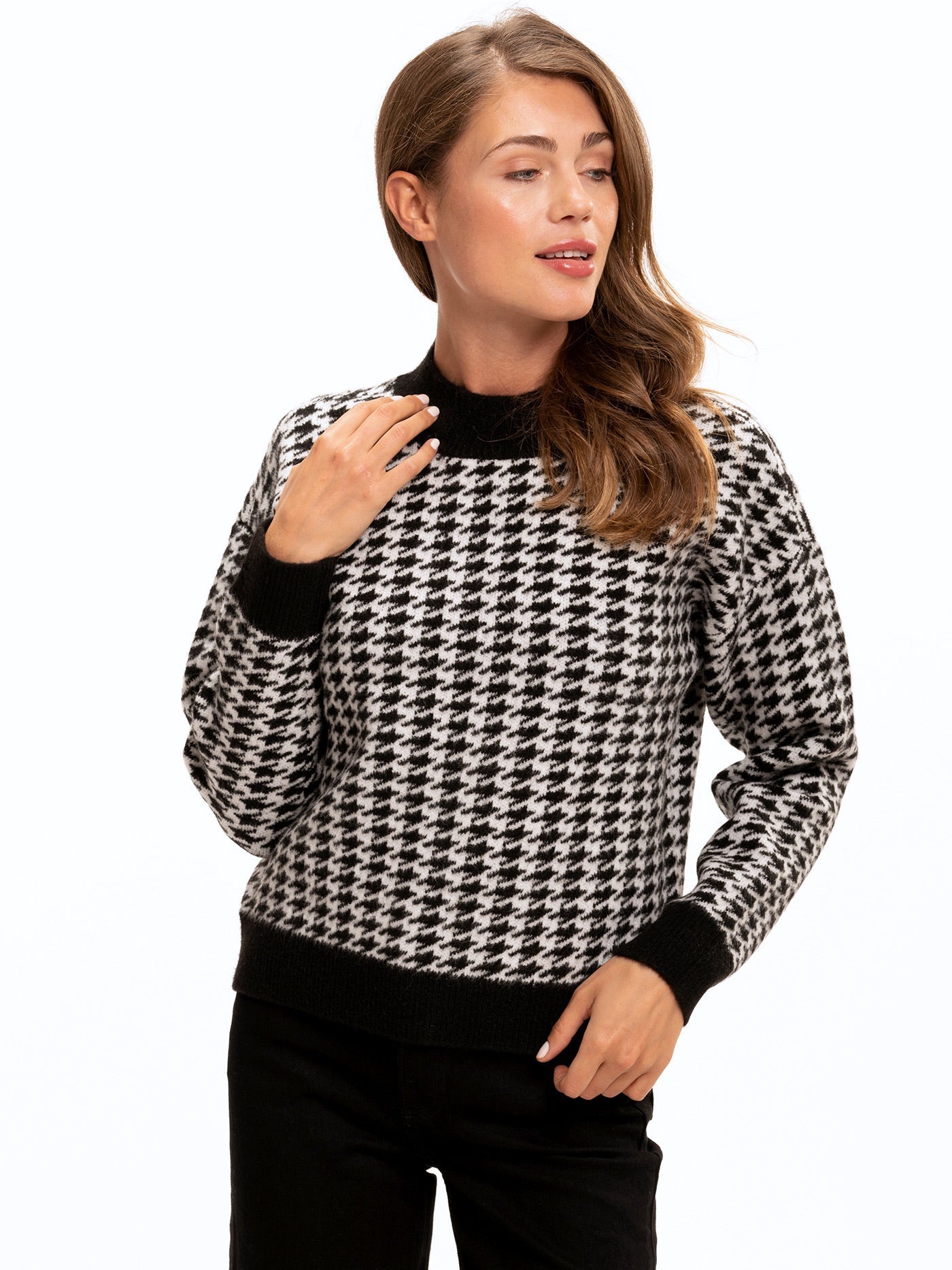 Model wearing a black and white houndstooth knit sweater with drop shoulder detail.