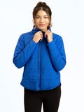 A woman wearing a vibrant royal blue Athene packable puffer jacket with a collared neck and full-length zip.