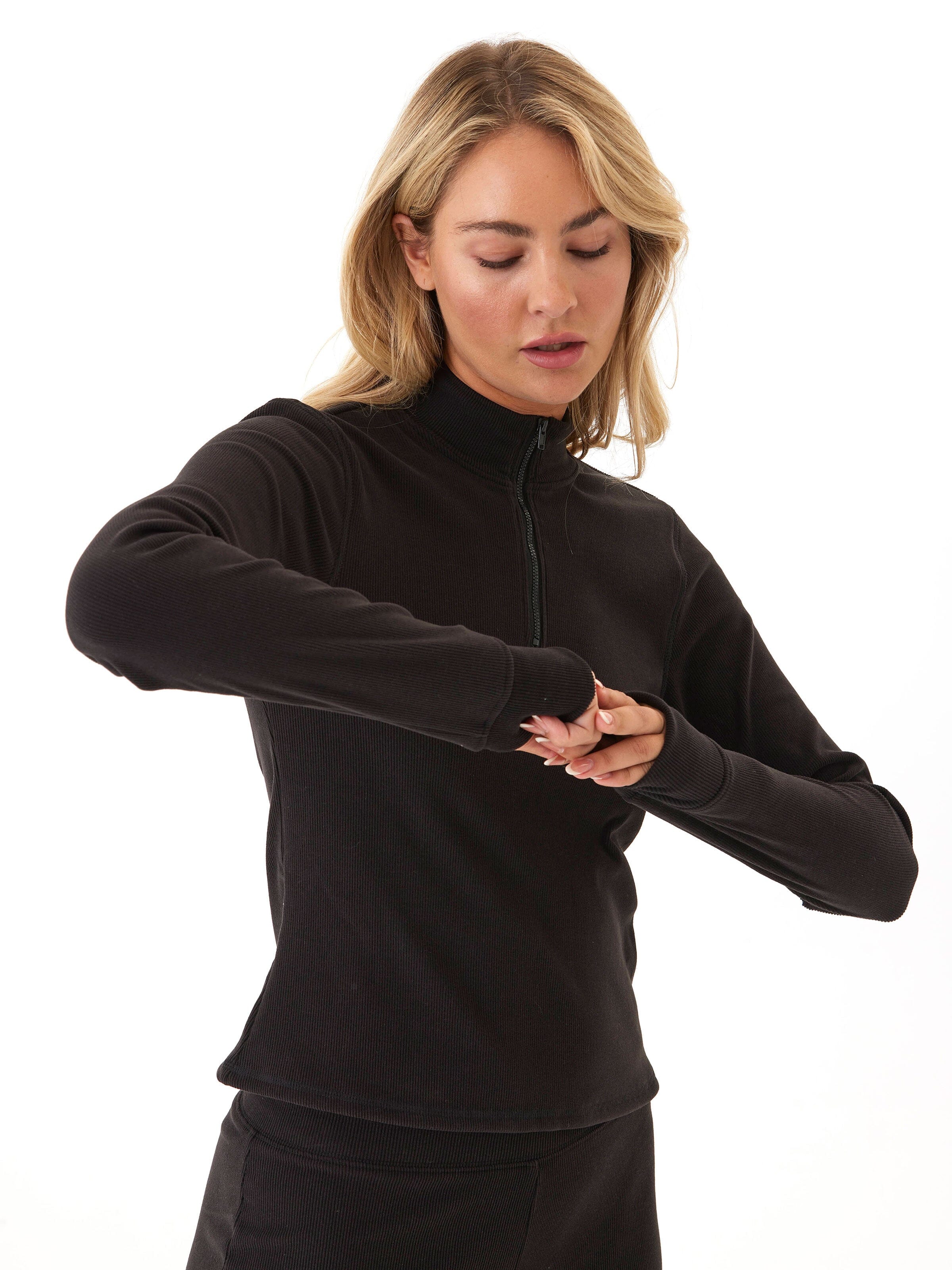 Model wearing a comfortable brushed rib 1/4 zip pullover with thumbholes in a neutral tone.