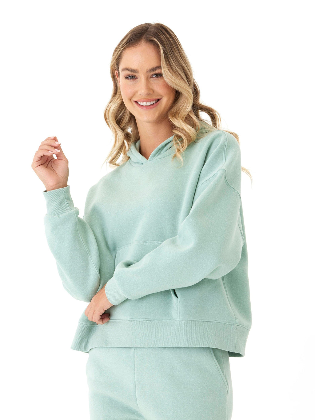 Woman wearing a soft mint green triblend fleece pullover hoodie with a hood and ribbed cuffs.