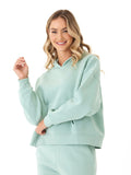 Woman wearing a soft mint green triblend fleece pullover hoodie with a hood and ribbed cuffs.