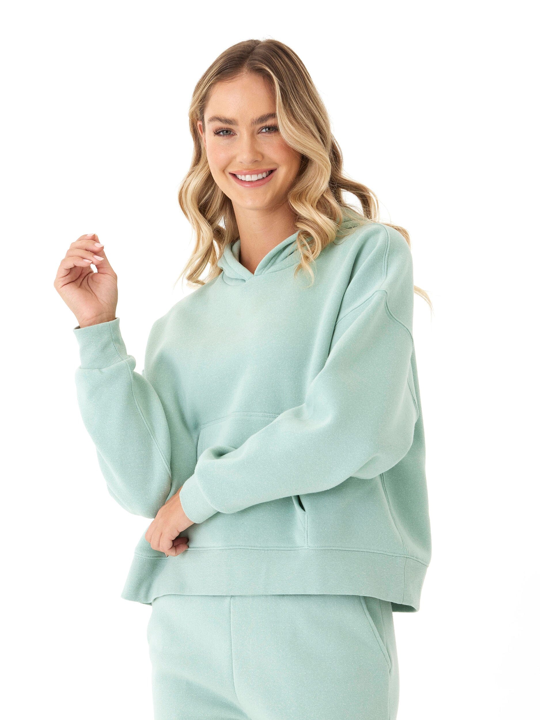 Woman wearing a soft mint green triblend fleece pullover hoodie with a hood and ribbed cuffs.