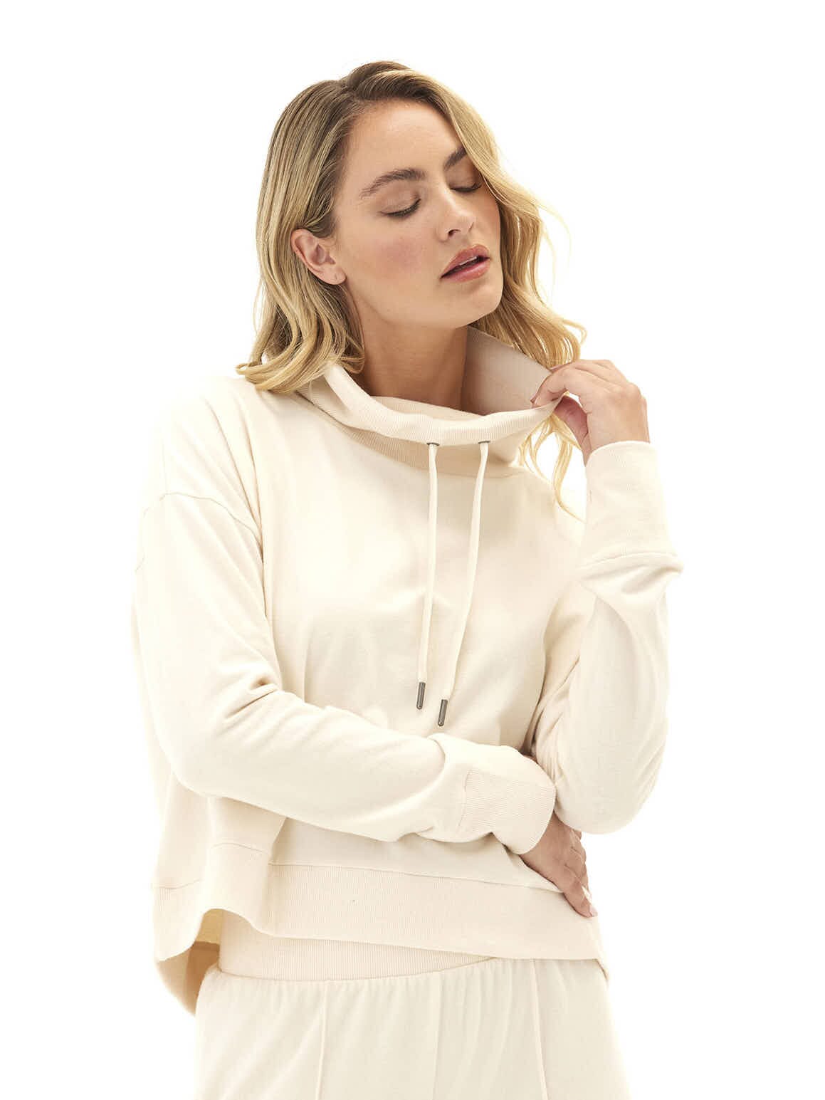 Woman wearing a cream Shai Cozy Fleece Cowl Neck Pullover with thumbholes