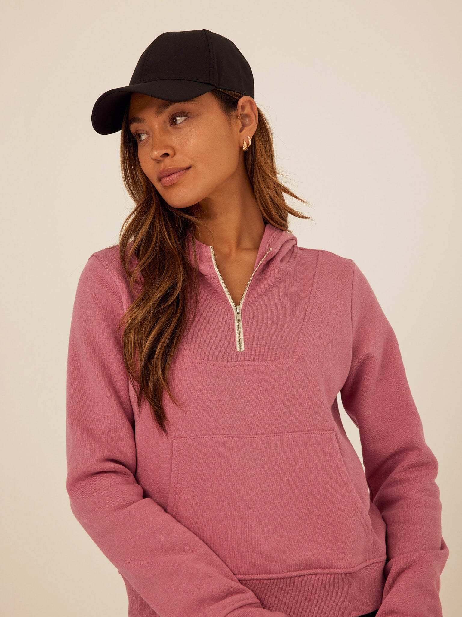 Women wearing a Mauve Tyra Triblend Fleece Quarter Zip Hoodie with thumbholes and pockets.