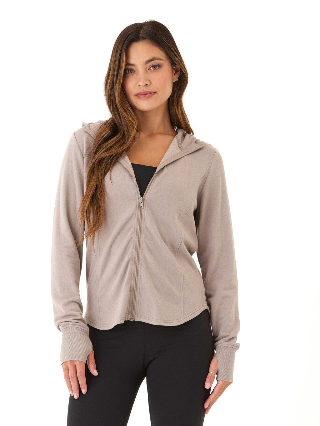 Woman wearing a fitted taupe feather fleece zip hoodie with long sleeves and thumbholes.